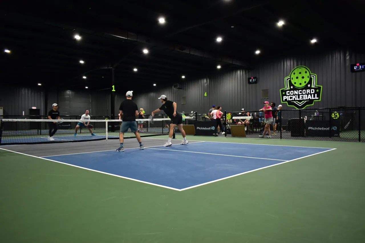 Players competing beneath the Concord Pickleball wall mark