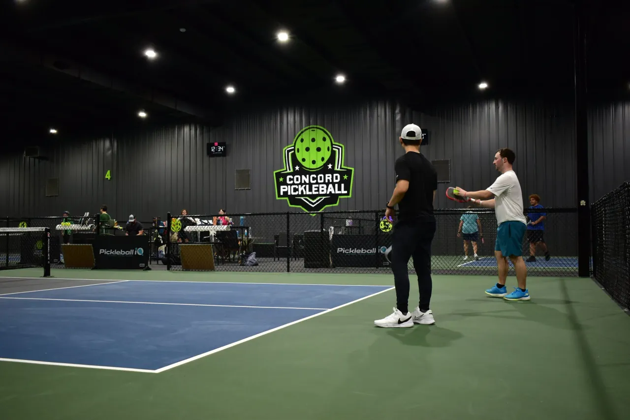 Players beside the Concord Pickleball wall mark inside the facility