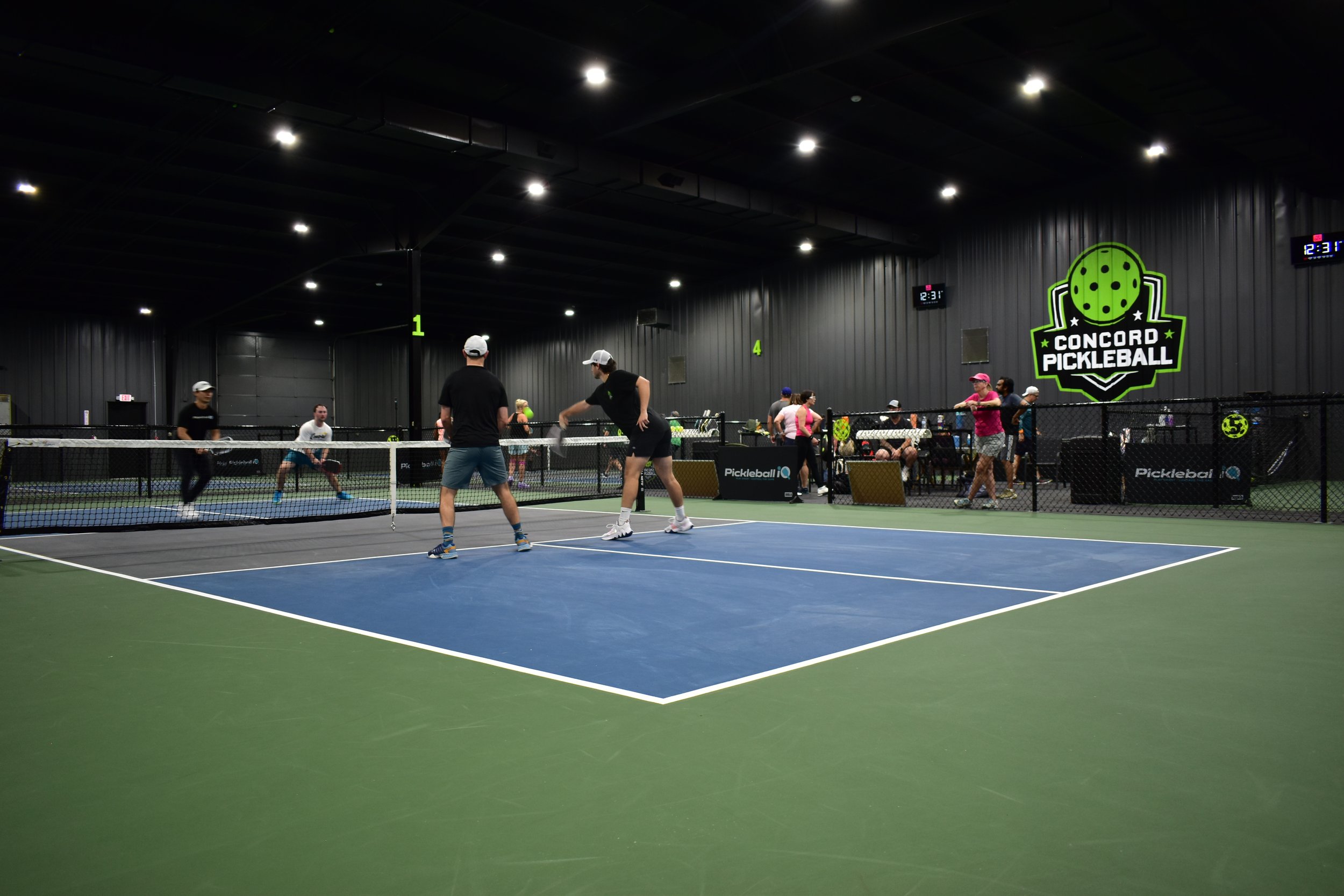 Players on the blue and green indoor courts at Concord Pickleball